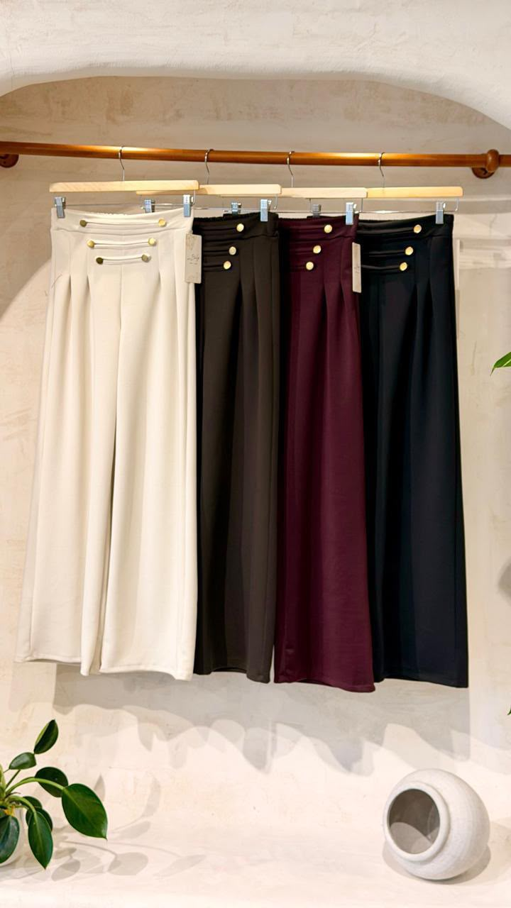 Foto original de pantalones en perchero, con variantes crema y negro entre otros colores